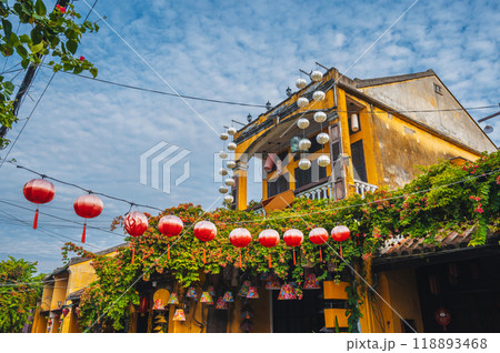 facade of an ancient Asian yellow house decorated with red Chinese lanterns for a holiday in old town in Hoi An in Vietnam 118893468