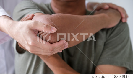 Female doctor hand rehab physical therapy by extending the pain shoulder of a patient. treatment with stretch exercises 118893935