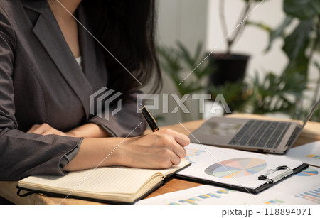 Businesswoman hand holding pen, analysis the graph with laptop at the home office for setting challenging business goals And planning to achieve the new target Businesswoman hand holding pen, analysis the graph with laptop at the home office for setting challenging business goals And planning to achieve the new target 118894071