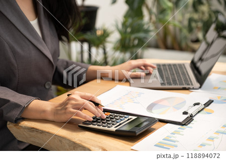 Businesswoman hand holding pen, analysis the graph with laptop at the home office for setting challenging business goals And planning to achieve the new target Businesswoman hand holding pen, analysis the graph with laptop at the home office for setting challenging business goals And planning to achieve the new target 118894072