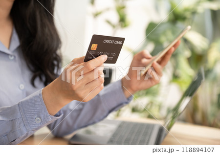 Consumer woman hand holding a mock up credit card, ready to spending pay online finance shopping according to discount products via smart phone from home office 118894107
