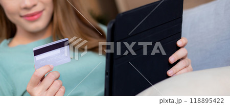 Young asian woman sitting on sofa using digital tablet shopping online with credit card buying. 118895422