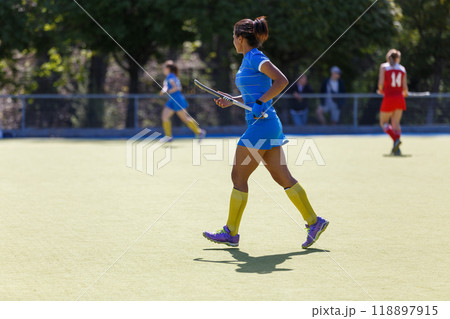 Young black field hockey player running with the stick on the turf Young black field hockey player running with the stick on the turf 118897915