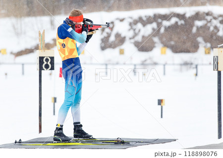 Athlete shooting in standing position at the range in a biathlon competition Athlete shooting in standing position at the range in a biathlon competition 118898076