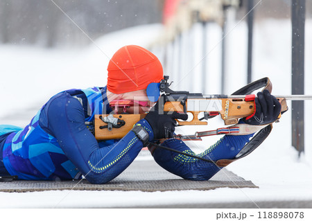 Athlete shooting in prone position at the range in a biathlon competition 118898078