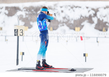 Athlete shooting in standing position at the range in a biathlon competition Athlete shooting in standing position at the range in a biathlon competition 118898079