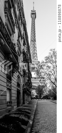 A quiet morning in Paris features empty cobblestone streets lined with elegant buildings, leading towards the iconic Eiffel Tower, framed by trees in a peaceful atmosphere. A quiet morning in Paris features empty cobblestone streets lined with elegant buildings, leading towards the iconic Eiffel Tower, framed by trees in a peaceful atmosphere. 118898878