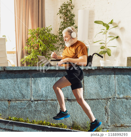 Elderly runner. Creative collage. Senior man wearing headphones, sitting at laptop, yet with runner's legs in motion below. 118899293