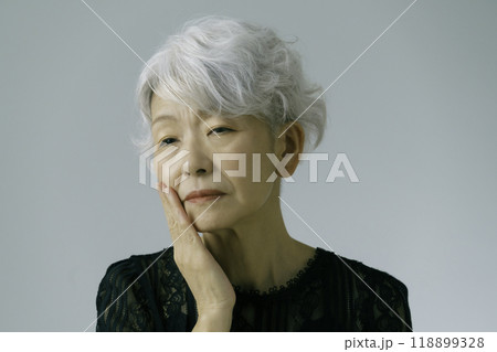 頬に手を当てる白髪のシニア女性 118899328