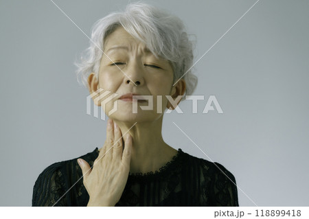 喉に手を当てる白髪のシニア女性 118899418