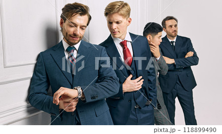 Professionals check time and engage in discussion, highlighting focus on punctuality and efficient organization against white studio background. Professionals check time and engage in discussion, highlighting focus on punctuality and efficient organization against white studio background. 118899490