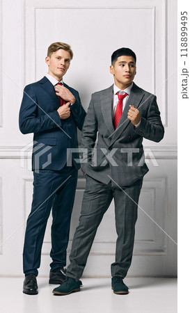 Team. Male Professionals showcasing modern elegance, both present strong and poised stances against white studio background. 118899495