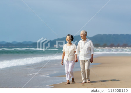 浜辺を仲良く手を繋ぎ歩く熟年カップル 浜辺を仲良く手を繋ぎ歩く熟年カップル 118900130