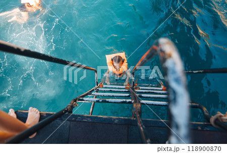 Experience the invigorating thrill of a refreshing summer swim from the boat ladders edge 118900870