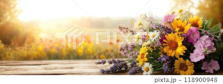 Wildflowers including vibrant daisies, cheerful sunflowers, and fragrant lavender are arranged in a rustic bouquet during golden hour. 118900948