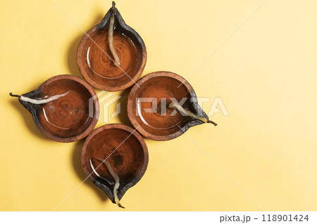 Happy Diwali - Traditional clay lamps arranged on yellow background during Diwali festival celebrations. Copy space for text. 118901424