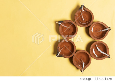 Happy Diwali - Hindu traditional clay diya arrangement for Diwali festival of lights celebration on yellow background. Happy Diwali - Hindu traditional clay diya arrangement for Diwali festival of lights celebration on yellow background. 118901426