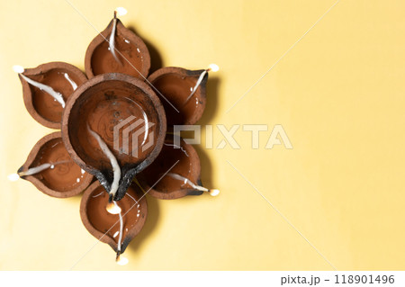 Happy Diwali - Traditional clay diya lamps are lit in a floral pattern on a yellow background during Diwali festival celebrations. Copy space for text. Happy Diwali - Traditional clay diya lamps are lit in a floral pattern on a yellow background during Diwali festival celebrations. Copy space for text. 118901496