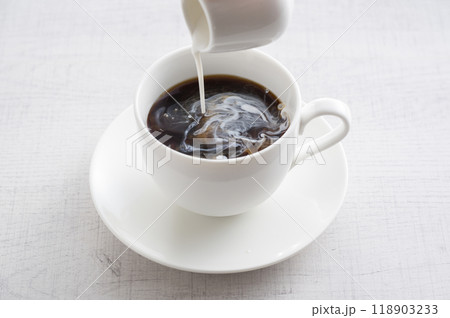白いカップに入ったコーヒーにコーヒーフレッシュを注ぐ 118903233