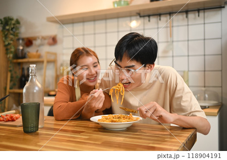 Young cheerful couple eating pasta, having lunch together at home. Love, relationships and food concept Young cheerful couple eating pasta, having lunch together at home. Love, relationships and food concept 118904191