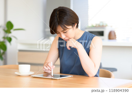 タッチペンを手にタブレット端末を操作する女性 118904390