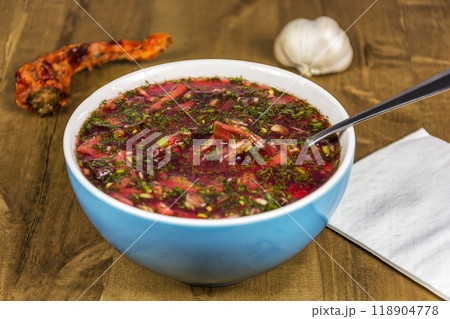 On a wooden table is a blue bowl of borscht. Red borscht in a blue porcelain bowl on a wooden table 118904778