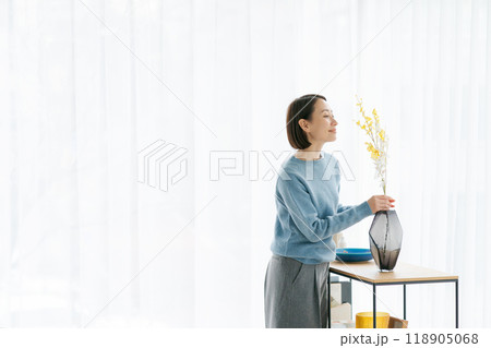 部屋にお花を飾る30代女性 118905068
