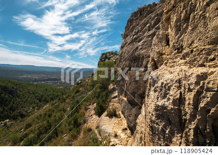 landscape of Rocky Cliffside Path Overlooking Lush Green Valley with Expansive Sky View 118905424