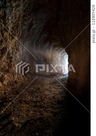 mysterious sunlit tunnel with rough rock walls 118905426