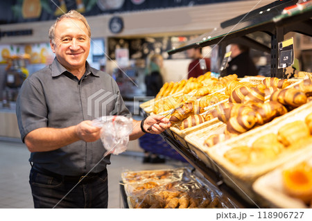 Man takes muffins on shelf of bakery section Man takes muffins on shelf of bakery section 118906727