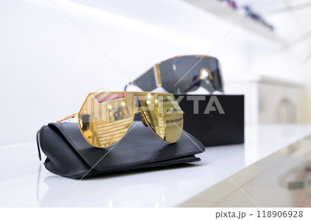 Gold and black lens fashion sunglasses displayed on black cases, showcasing modern minimalism, luxury eyewear, premium accessories, reflecting elegant design, retail presentation, stylish chic look. 118906928