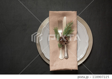 Christmas table place setting with silverware and dark evergreen decor. Top view. Holiday background. 118907225