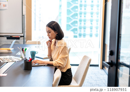 片肘をついて思考を巡らせながらパソコン作業をしている女性 118907931