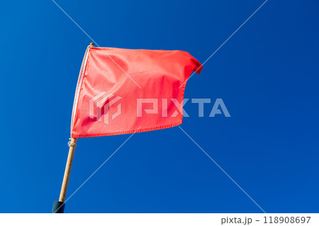 Warning red flag is waving on strong wind above blue sky 118908697