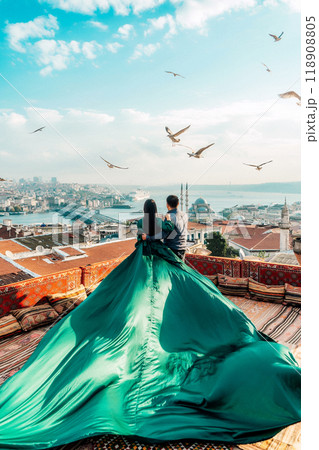 Couple man and woman in green dress with long train on terrace view of Bosphorus in Istanbul Couple man and woman in green dress with long train on terrace view of Bosphorus in Istanbul 118908805