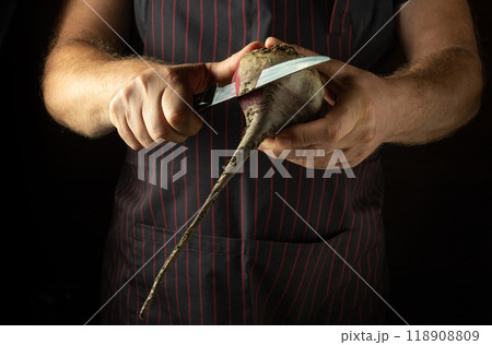 A chef peels raw beets with a knife. Preparing to cook a dietary vegetable dish in a restaurant kitchen. Advertising space A chef peels raw beets with a knife. Preparing to cook a dietary vegetable dish in a restaurant kitchen. Advertising space 118908809