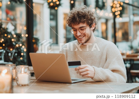 Young man smiling while shopping online with a credit card 118909112