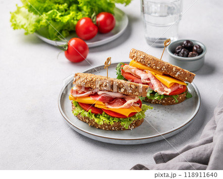 Two toast club sandwiches made of grain bread with cheddar cheese and bacon stuffed with tomatoes  118911640