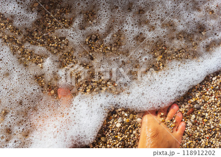 A persons foot is resting gently on the warm sand at the beach A persons foot is resting gently on the warm sand at the beach 118912202