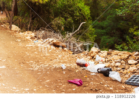 a large, unsightly pile of trash located on the side of a dirt road 118912226