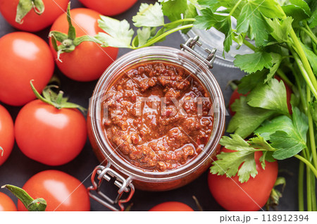 Homemade tomato sauce for pizza or pasta in a jar on a gray background with fresh vegetables  118912394