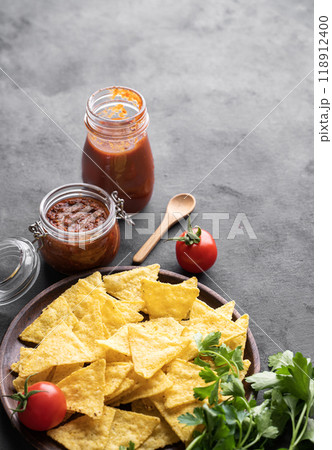 Nachos or tortilla with spicy tomato sauce on a plate with fresh vegetables and herbs Nachos or tortilla with spicy tomato sauce on a plate with fresh vegetables and herbs 118912400