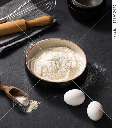 Flour, eggs and rolling pin on a dark  background close up. Organic baking ingredients. 118912427