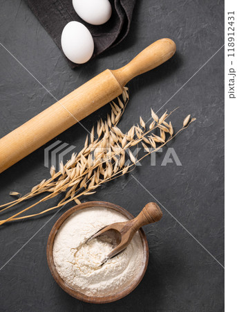 Oatmeal, eggs and rolling pin on a dark  background. Organic baking ingredients. 118912431