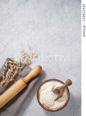 Oatmeal in a wooden bowl with a scoop, rolling pin and napkin on a blue background with branches Oatmeal in a wooden bowl with a scoop, rolling pin and napkin on a blue background with branches 118912435