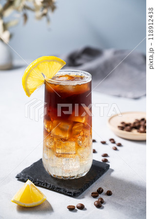Coffee with tonic in a tall glass with ice and lemon on a light blue background with coffee beans Coffee with tonic in a tall glass with ice and lemon on a light blue background with coffee beans 118912438