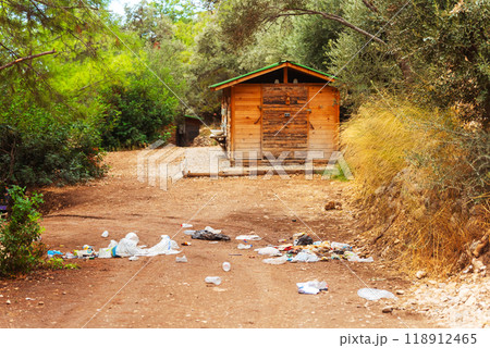 large unsightly pile of trash located near small wooden house in forest 118912465