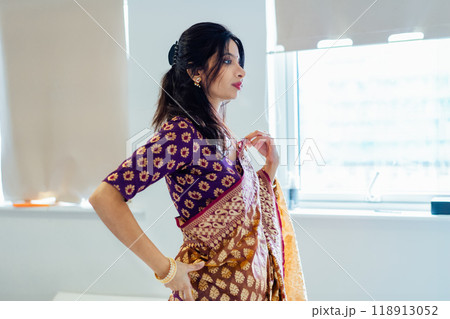 Indian woman delicately putting traditional beautiful saree and traditional jewellery getting ready for ethnic festive celebration. Indian culture and ritual holidays in modern life. Selective focus 118913052