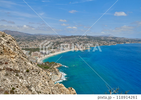 Breathtaking Panoramic View of Calpe's Turquoise Bay from Majestic Cliffside Overlooking Iconic Penon de Ifach Rock Formation. Stunning Costa Blanca Seascape: Calpe's Golden Beaches and Azure Waters Breathtaking Panoramic View of Calpe's Turquoise Bay from Majestic Cliffside Overlooking Iconic Penon de Ifach Rock Formation. Stunning Costa Blanca Seascape: Calpe's Golden Beaches and Azure Waters 118914261