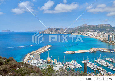 Panoramic Vista of Calpe Spain Coastal Town Yacht Marina Blue Sky Sunny Day Tourism Destination Mediterranean Lifestyle. Aerial View Calpe Spain Costa Blanca Penon de Ifach Rock Mediterranean Sea 118914279